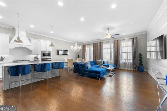 living room featuring dark wood-type flooring, ceiling fan with notable chandelier, and ornamental molding