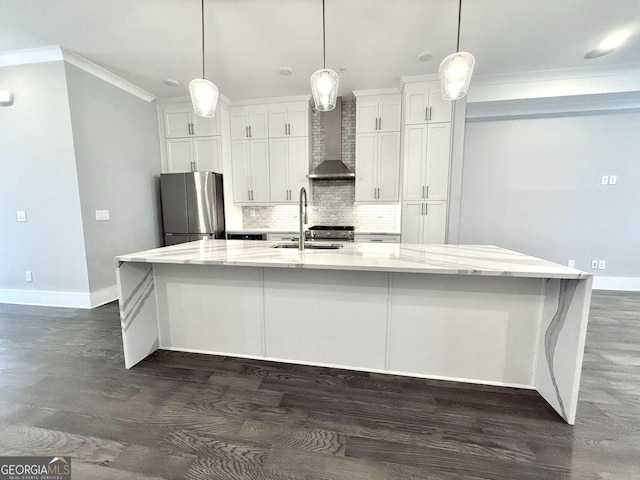 kitchen featuring a large island, wall chimney exhaust hood, stainless steel fridge, and decorative light fixtures