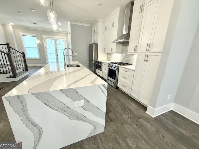 kitchen featuring decorative light fixtures, white cabinetry, sink, stainless steel appliances, and wall chimney exhaust hood