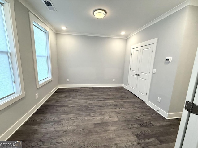 empty room with ornamental molding and dark wood-type flooring