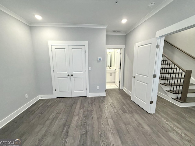 unfurnished bedroom with crown molding, sink, dark wood-type flooring, and a closet