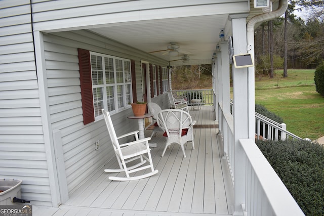 wooden terrace featuring ceiling fan, a lawn, and a porch