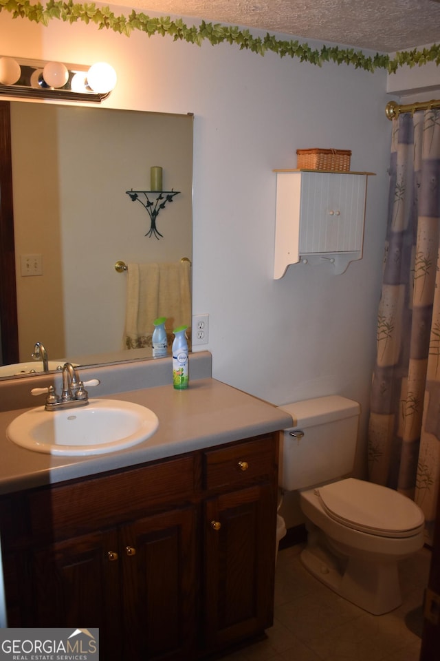 bathroom with a textured ceiling, toilet, tile patterned flooring, and vanity