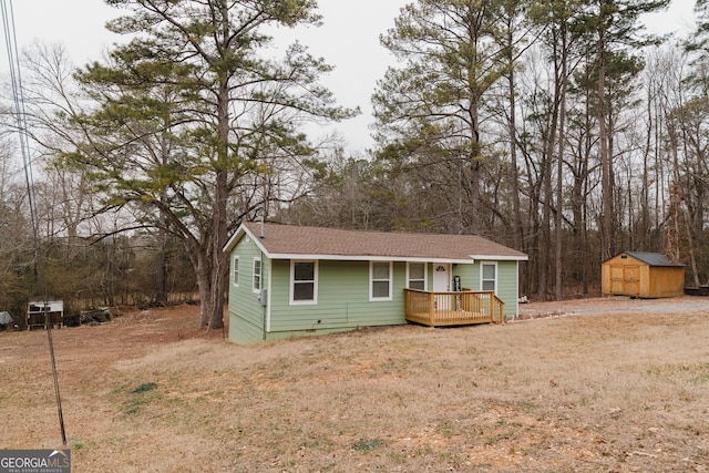 single story home featuring a wooden deck, a front yard, and a storage unit