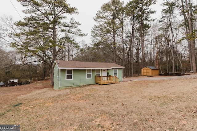 ranch-style house with a front yard, a deck, and a storage unit