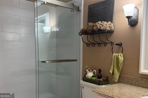 bathroom with vanity, a shower with door, and toilet