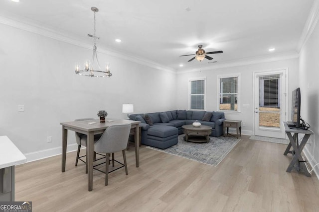 living room with crown molding, ceiling fan with notable chandelier, and light wood-type flooring