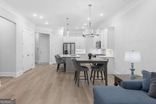 dining area featuring ornamental molding, sink, and light wood-type flooring