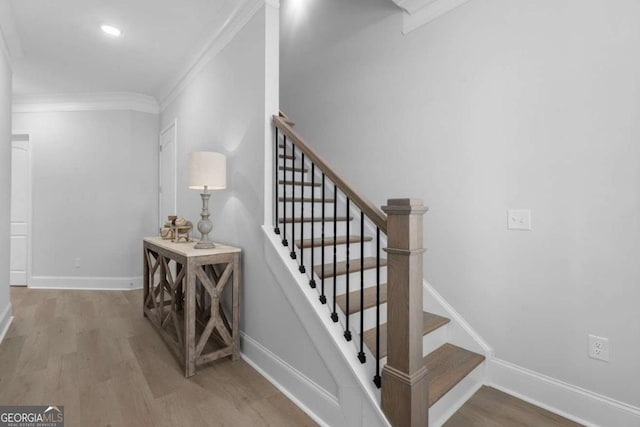 stairway with hardwood / wood-style flooring and ornamental molding