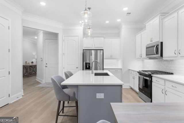 kitchen with an island with sink, appliances with stainless steel finishes, sink, and white cabinets