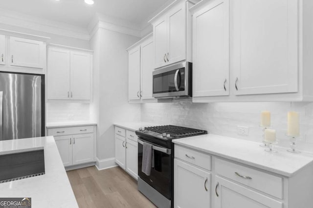 kitchen featuring tasteful backsplash, ornamental molding, appliances with stainless steel finishes, and white cabinets