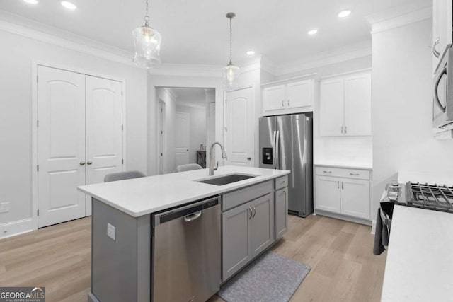 kitchen featuring sink, a center island with sink, pendant lighting, stainless steel appliances, and white cabinets