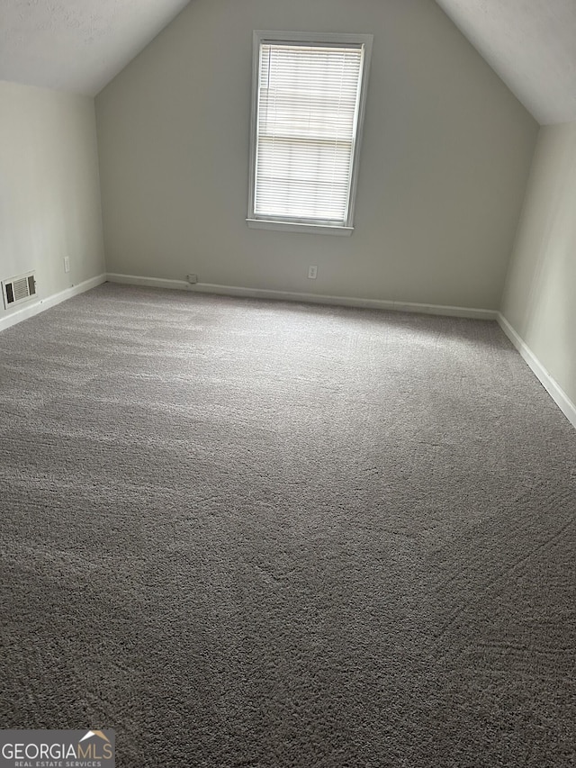 additional living space featuring vaulted ceiling, carpet, visible vents, and baseboards