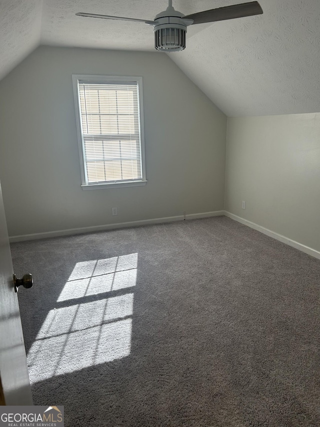 bonus room with lofted ceiling, baseboards, dark carpet, and a textured ceiling