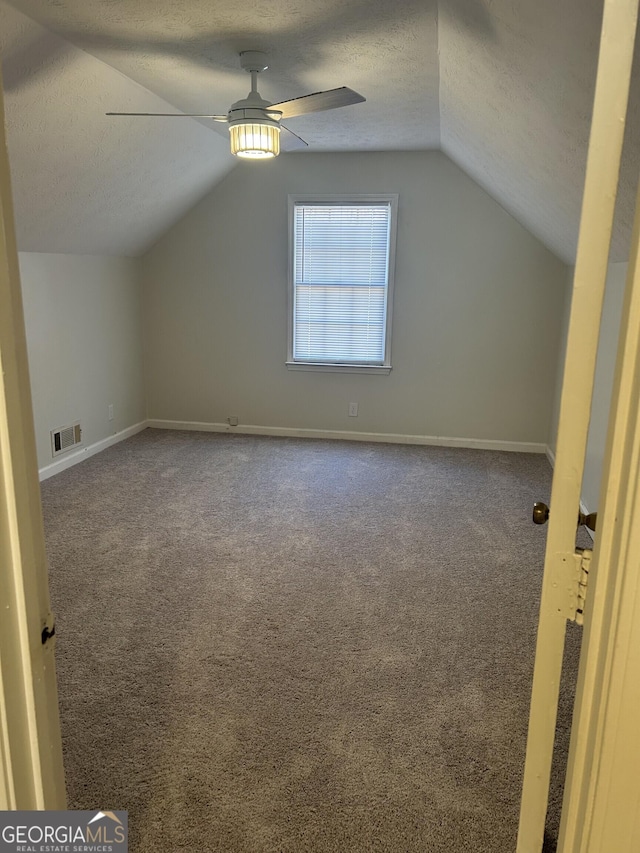 bonus room with a textured ceiling, carpet floors, visible vents, baseboards, and a ceiling fan