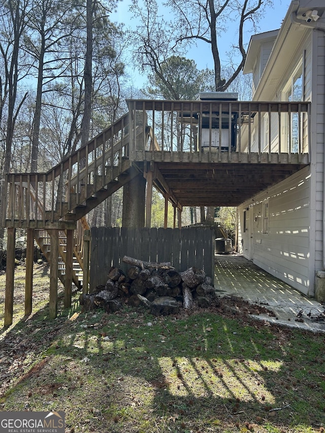 view of property exterior with a patio area, fence, stairway, and a wooden deck