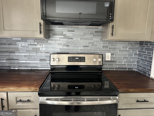 kitchen featuring stainless steel range with electric stovetop, black microwave, butcher block countertops, and tasteful backsplash