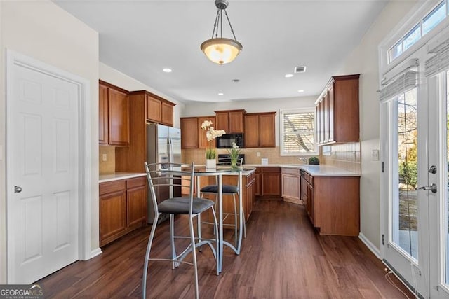 kitchen with tasteful backsplash, a breakfast bar, dark hardwood / wood-style flooring, and decorative light fixtures