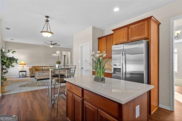 kitchen featuring dark hardwood / wood-style flooring, stainless steel fridge with ice dispenser, decorative light fixtures, and a center island