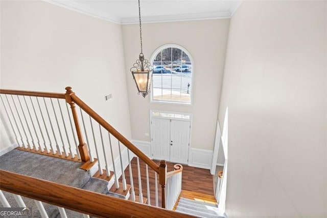 entrance foyer with an inviting chandelier, ornamental molding, and hardwood / wood-style flooring