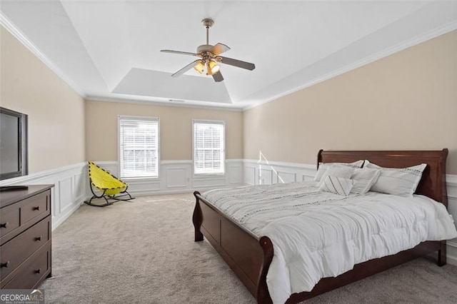 carpeted bedroom with ceiling fan, ornamental molding, and a tray ceiling