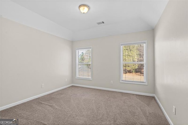 carpeted empty room featuring vaulted ceiling