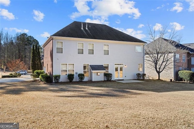 rear view of house with french doors and a lawn