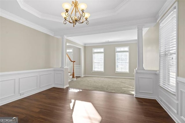 interior space featuring a tray ceiling, crown molding, and ornate columns