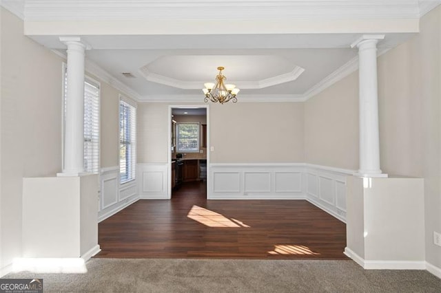 unfurnished dining area with ornamental molding, decorative columns, a raised ceiling, and dark colored carpet