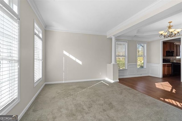 unfurnished living room featuring an inviting chandelier, ornamental molding, carpet, and a wealth of natural light