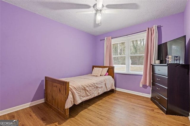 bedroom with light hardwood / wood-style floors, a textured ceiling, and ceiling fan