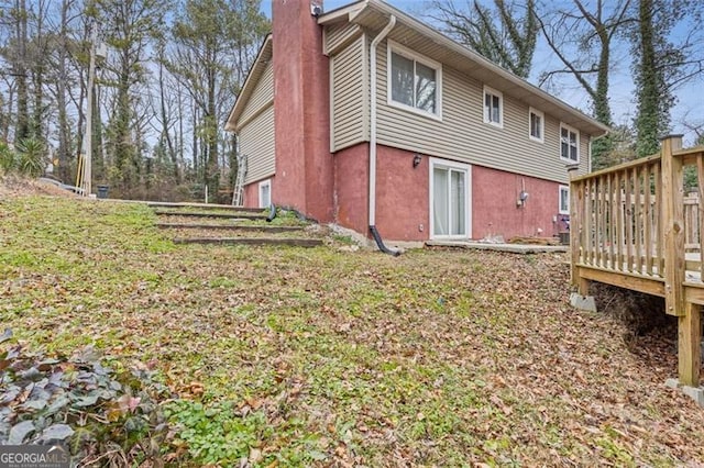 rear view of property featuring a wooden deck and a yard