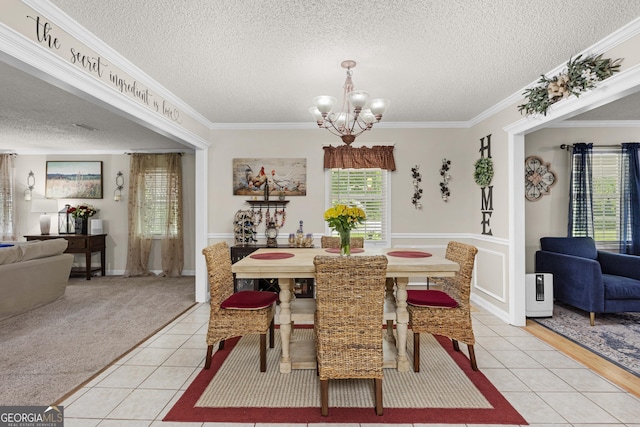 tiled dining area with a textured ceiling, a notable chandelier, and ornamental molding