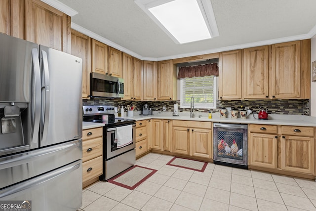 kitchen featuring appliances with stainless steel finishes, sink, backsplash, light tile patterned flooring, and ornamental molding