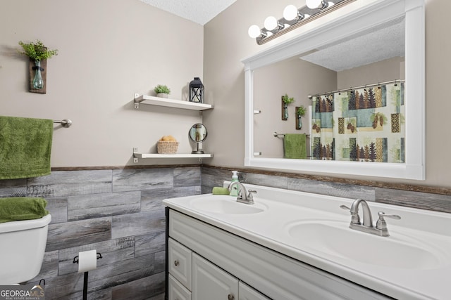 bathroom featuring toilet, a textured ceiling, and vanity