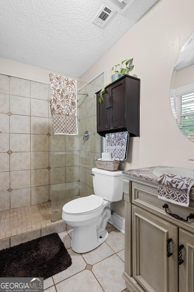 bathroom with a textured ceiling, tile patterned floors, vanity, toilet, and tiled shower