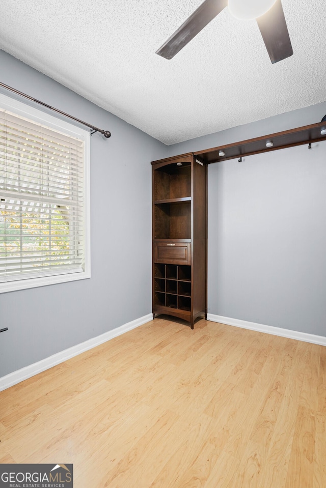 unfurnished bedroom featuring ceiling fan, a textured ceiling, and light wood-type flooring