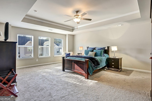 carpeted bedroom with ornamental molding, ceiling fan, and a raised ceiling