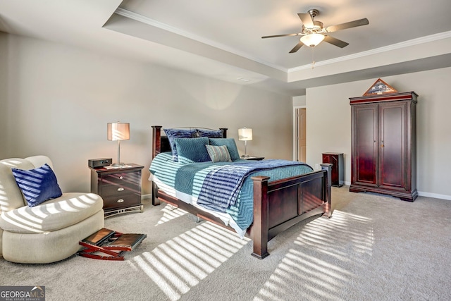 bedroom featuring ceiling fan, a tray ceiling, ornamental molding, and light carpet