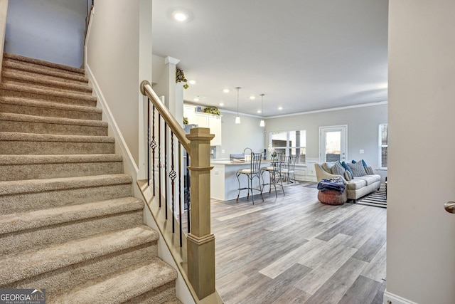 staircase featuring crown molding and wood-type flooring