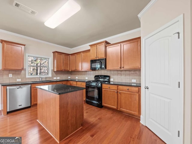 kitchen with black appliances, a kitchen island, decorative backsplash, sink, and crown molding