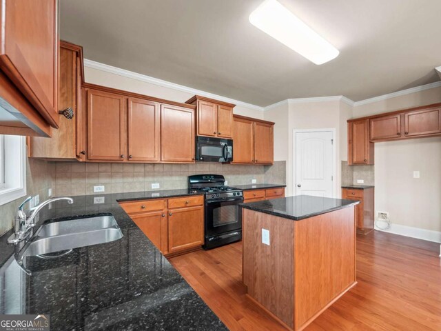 kitchen with black appliances, dark stone counters, a kitchen island, and sink