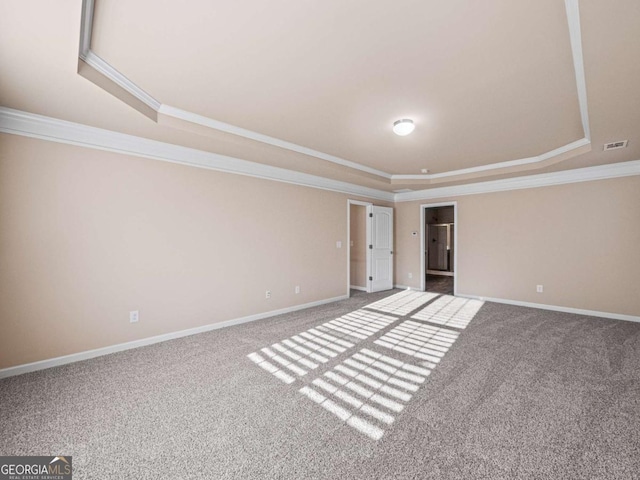 empty room with carpet flooring, ornamental molding, and a tray ceiling