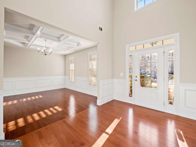 entryway featuring hardwood / wood-style floors, coffered ceiling, a healthy amount of sunlight, and a notable chandelier