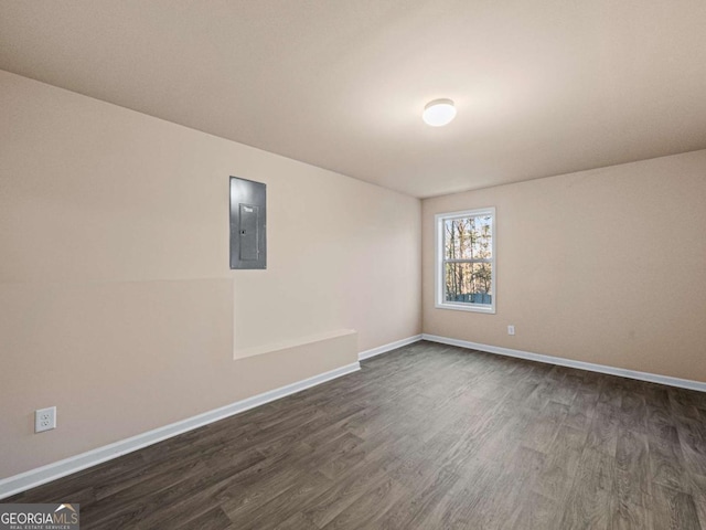 spare room featuring electric panel and dark wood-type flooring