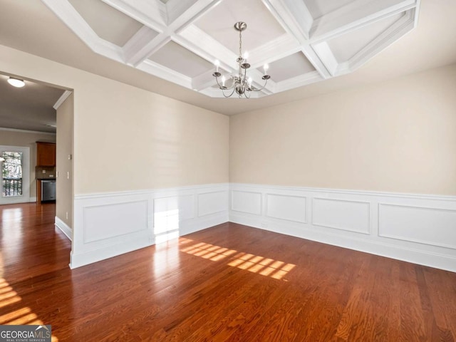 spare room featuring coffered ceiling, dark hardwood / wood-style floors, a notable chandelier, and beam ceiling