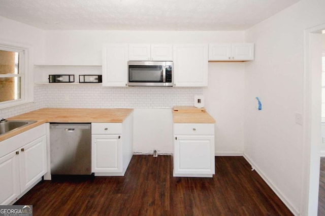 kitchen with white cabinetry, wood counters, appliances with stainless steel finishes, and dark wood-type flooring