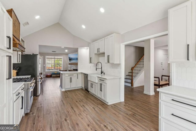 kitchen featuring white cabinets, stainless steel appliances, sink, backsplash, and kitchen peninsula