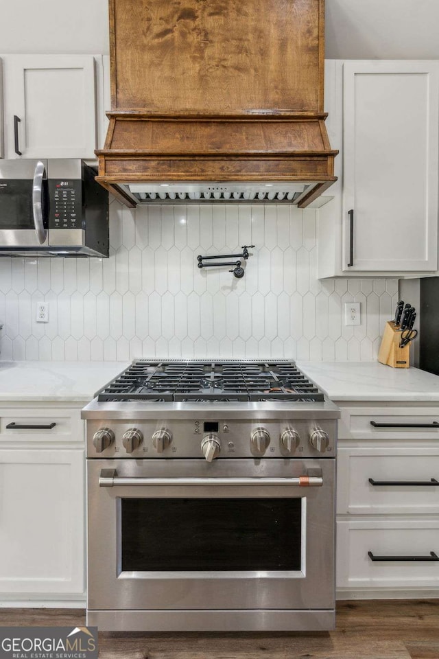 kitchen with white cabinets, appliances with stainless steel finishes, and tasteful backsplash