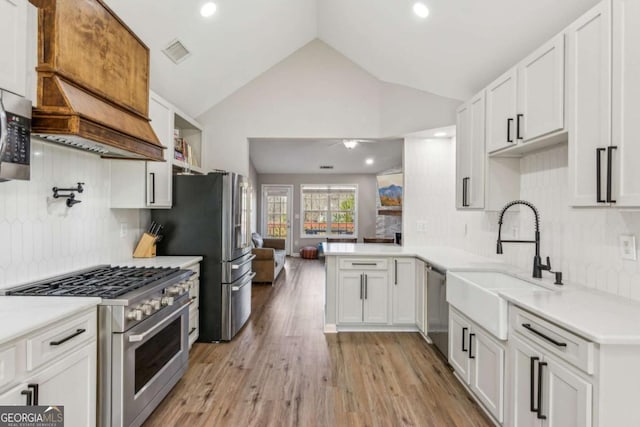 kitchen featuring kitchen peninsula, white cabinetry, lofted ceiling, and stainless steel appliances